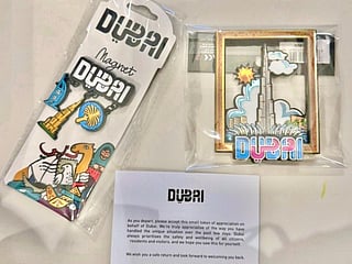 The thank-you note accompanies souvenirs that include Dubai-themed fridge magnets featuring the Burj Khalifa and a license plate magnet featuring Dubai skyline, among others.