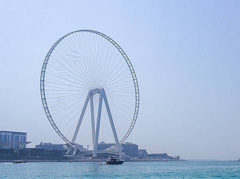 People sunbathe along the Marina beach near the Ain Dubai Ferris wheel.