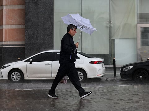 A resident braves the wind and rain at Al Khan, Sharjah