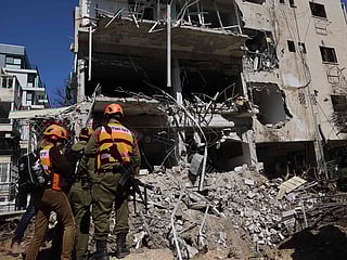 Israeli emergency service personnel gather at the site of an Iranian missile strike in Tel Aviv. 