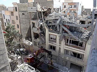 Firefighters look for victims and inspect damages at a residential building following Israeli air strikes in southern Tehran on March 27, 2026. 