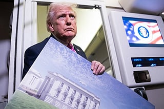 President Donald Trump holds a rendering of the proposed East Wing of the White House while speaking to members of the media onboard Air Force One on March 29, 2026 while en route to Joint Base Andrews, Maryland from West Palm Beach Florida.