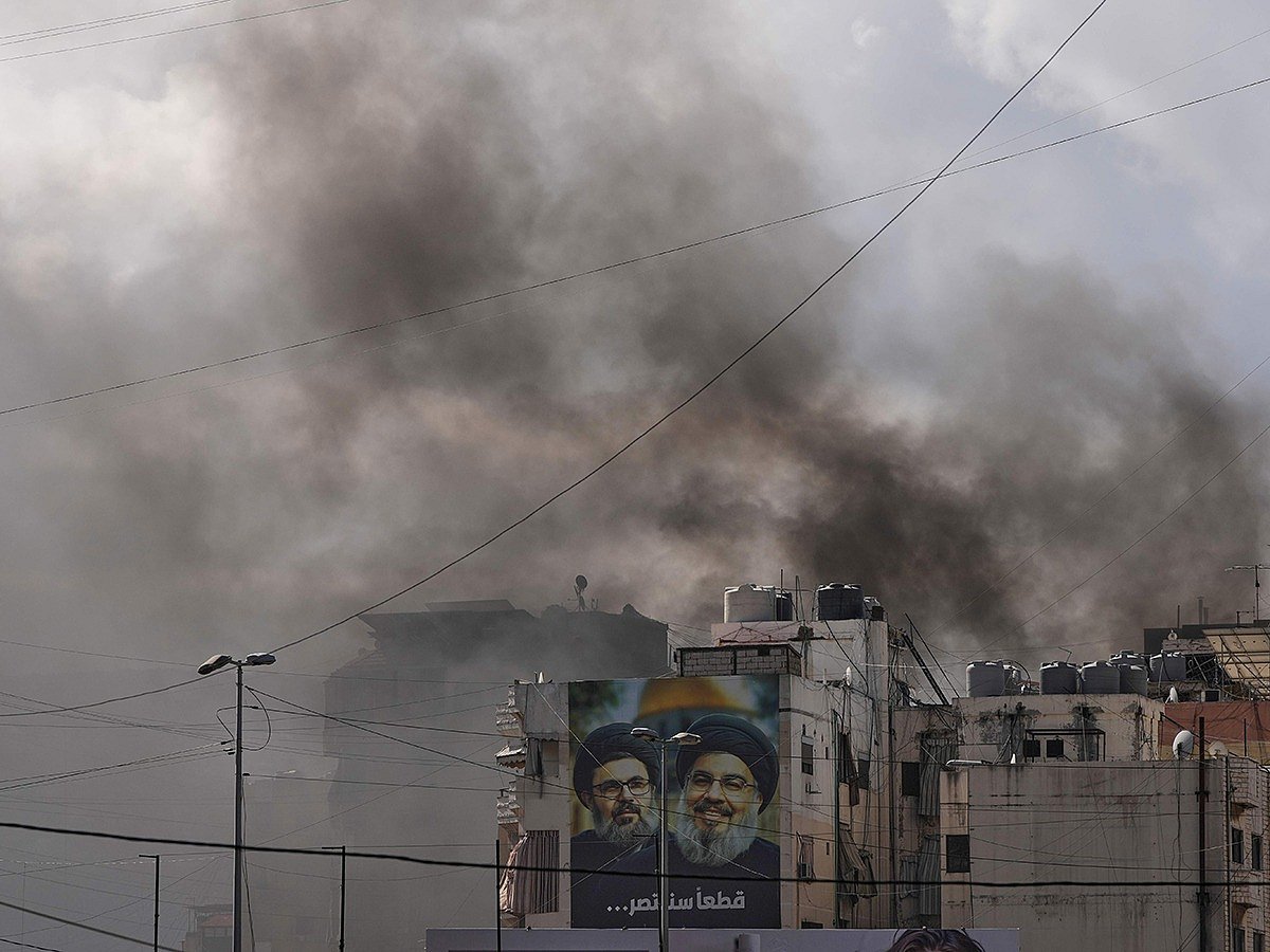 Portraits of Hezbollah's late leaders Hassan Nasrallah, right, and his cousin, Hashem Safieddine, are seen, as smoke rises following an Israeli airstrike in Dahiyeh, Beirut's southern suburbs, Lebanon, Monday, March 30, 2026. 