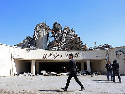 A media representative walks past a heavily damaged building following a strike at the Azadi Sport Complex in Tehran on April 3, 2026.