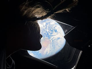 This handout picture by an Artemis II crew member provided by NASA shows Artemis II mission specialist Christina Koch looking back at earth through the window of the Orion spacecraft on April 2, 2026.