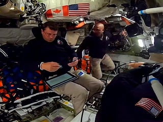 This screengrab from a NASA live broadcast video footage shows NASA astronaut and Artemis II Commander Reid Wiseman (L) and NASA astronaut and Artemis II pilot Victor Glover working indside the Orion spacecraft as they pass the halfway point between Earth and the Moon on the way to their planned lunar flyby in the Orion spacecraft, on April 3, 2026.