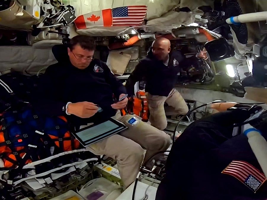 This screengrab from a NASA live broadcast video footage shows NASA astronaut and Artemis II Commander Reid Wiseman (L) and NASA astronaut and Artemis II pilot Victor Glover working indside the Orion spacecraft as they pass the halfway point between Earth and the Moon on the way to their planned lunar flyby in the Orion spacecraft, on April 3, 2026.
