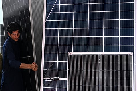This photograph taken on April 4, 2026 shows a worker arranging solar panels at an electrical appliance store in Rawalpindi as Pakistan faces energy supply chain disruptions amid the Middle East war.