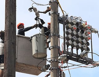Manila Electric Co (Meralco) linemen repair power meters atop electricity post at the port area of Metro Manila, Philippines.