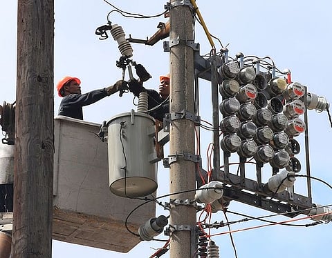 Manila Electric Co (Meralco) linemen repair power meters atop electricity post at the port area of Metro Manila, Philippines.