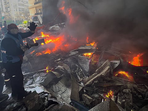 A rescue worker extinguishes burning cars at the site of an Israeli airstrike in central Beirut, Lebanon.