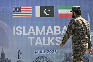 A Pakistani Ranger walks past a billboard for the US-Iran peace talks in Islamabad on April 12, 2026.
