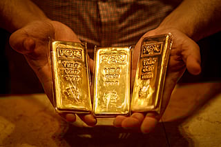 An Emirati gold dealer holds bars of gold in a shop in the Dubai Gold Souk on April 13, 2025.