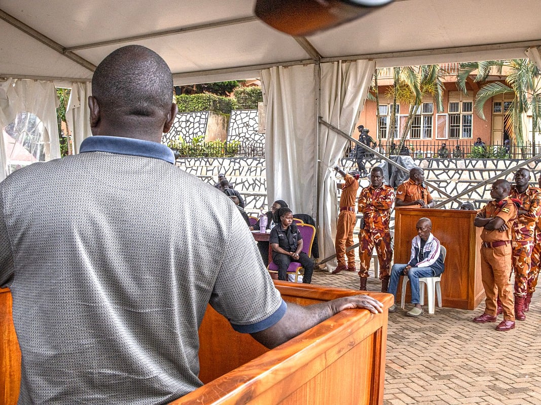 A parent (L) of one of the victims in the Ggaba killings, offers his testimony to the events during the anticipated public trial of Christopher Okello Onyum (4th R), suspected in the killing of four toddlers at a daycare in Ggaba, at the Ggaba Community Church Grounds in Kampala on April 13, 2026.