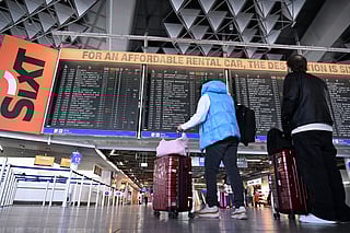 Passengers check a flight information display at Frankfurt Airport, Frankfurt am Main, western Germany, on April 15, 2026, as cabin crew union UFO urged members of Lufthansa cabin crew to stage a strike in a dispute over pay and pensions.