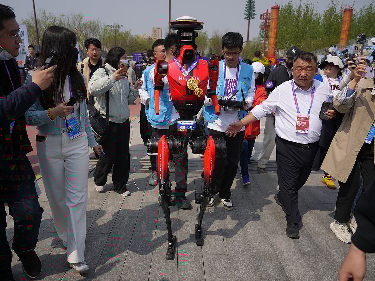 The winner of the humanoid robot half-marathon from Honor is chased by journalists after a press conference at the Beijing E-Town Half Marathon and Humanoid Robot Half-Marathon on the outskirts of Beijing.