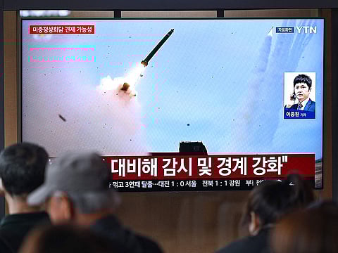 People watch a television screen showing a news broadcast with file footage of a North Korean missile test, at a train station in Seoul on April 19, 2026.