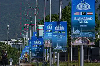 Workers walk past billboards near the Serena Hotel ahead of the second round of negotiations between the U.S. and Iran, in Islamabad, Pakistan, Monday, April 20, 2026. (AP Photo/Anjum Naveed)