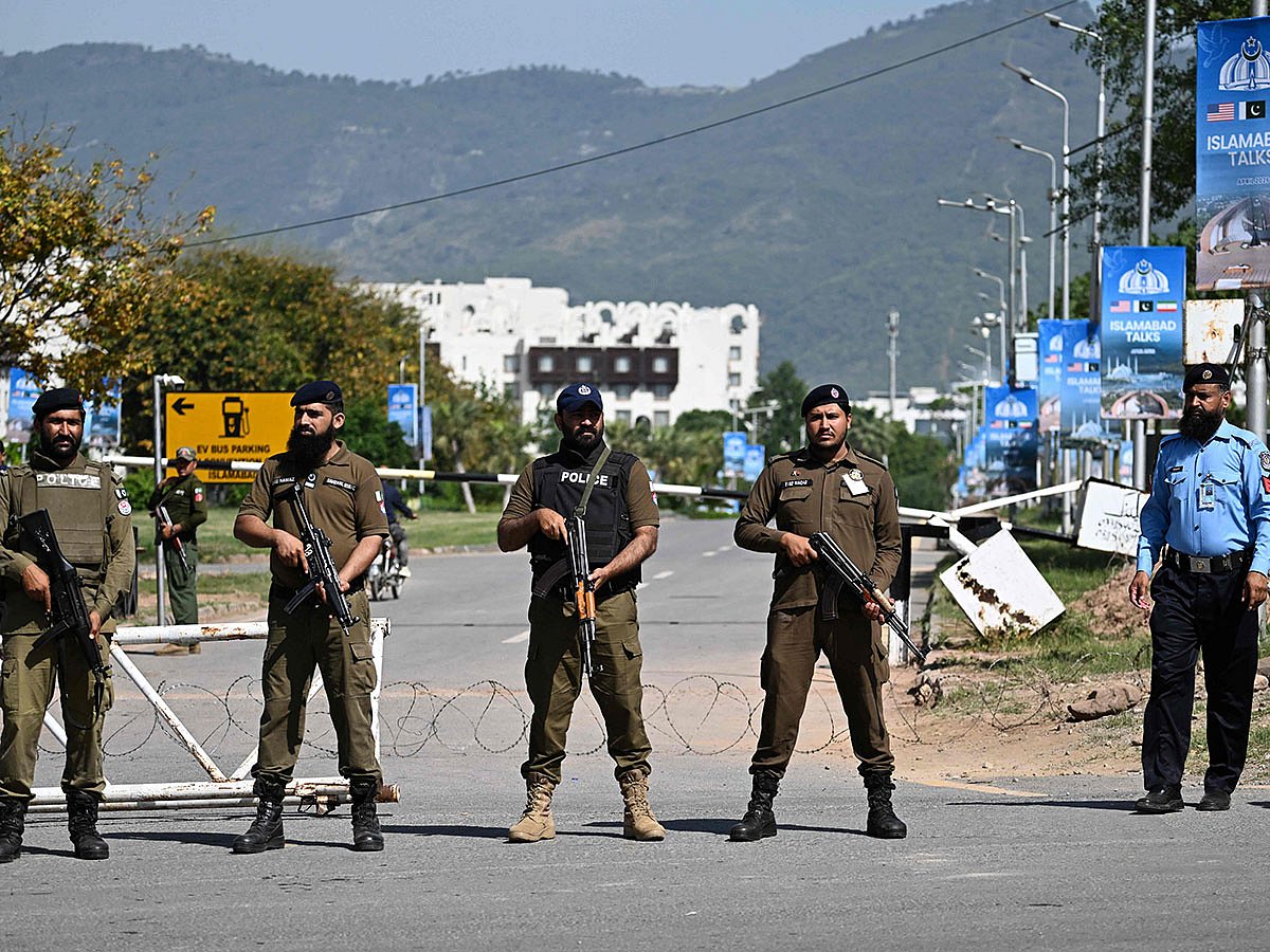 Security personnel stand guard at a security checkpost along a road temporarily closed near the Serena Hotel at the Red Zone area in Islamabad ahead of anticipated US-Iran peace talks..