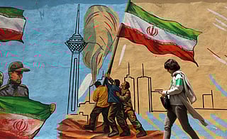 An Iranian woman walks past an anti-USA and anti-Israel mural, in Tehran on April 21 2026, amid a ceasefire in the region.
