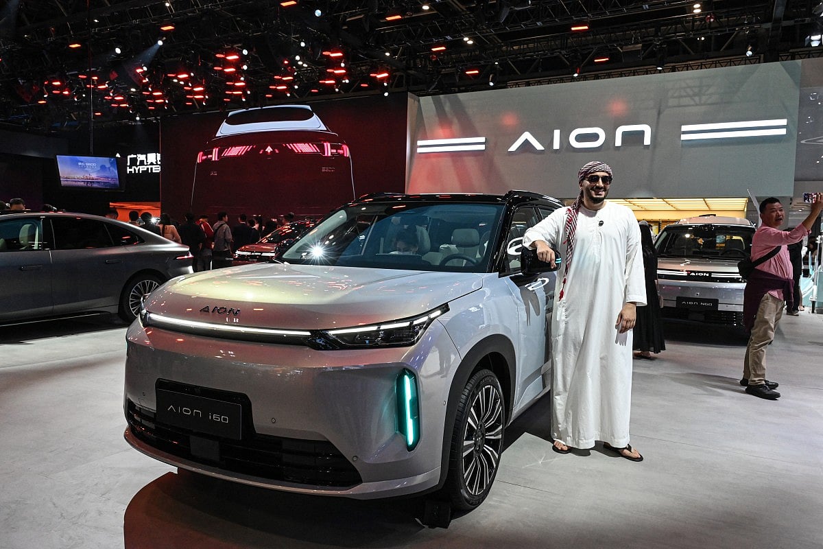 A man poses for photographs beside Aion’s i60 car at the Beijing Auto Show in Beijing on April 24, 2026.