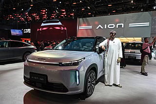 A man poses for photographs beside Aion’s i60 car at the Beijing Auto Show in Beijing on April 24, 2026.