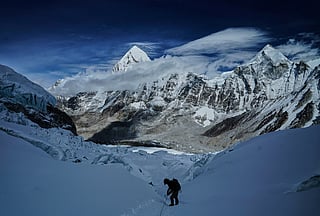 Mount Pumori, centre left, looms in the background as a mountaineer negotiates Khumbu Icefall to descend to Everest Base Camp, in Nepal, May 4, 2025.
