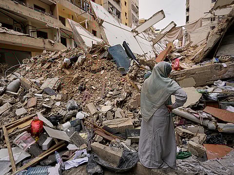 A woman stands by the rubble of a destroyed building, following a ceasefire between Hezbollah and Israel, in Dahiyeh, Beirut's southern suburbs, Lebanon. AP