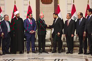 This handout photograph taken and released by the Iraqi Presidency Press Office on April 27, 2026 shows Iraq's President Nizar Amede (4th L) shaking hands with newly Iraq's Prime Minister designated Ali al-Zaidi (4th R), surrounded by Iraqi political leaders, at the Presidential Palace in Bagdad.