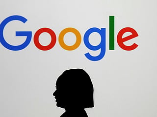 A woman walks by a giant screen displaying the Google logo at an event at the Paris Google Lab on the sidelines of the AI Action Summit in Paris 