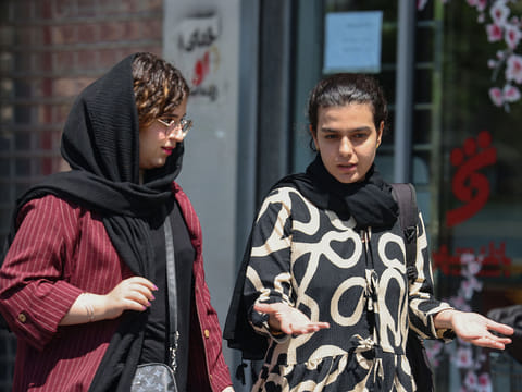 Iranian women walk at the Revolution Square in Tehran. 