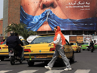 Commuters walk past an anti-US billboard referring to President Donald Trump and the Strait of Hormuz, installed on a building at the Valiasr Square in Tehran on May 2, 2026. 