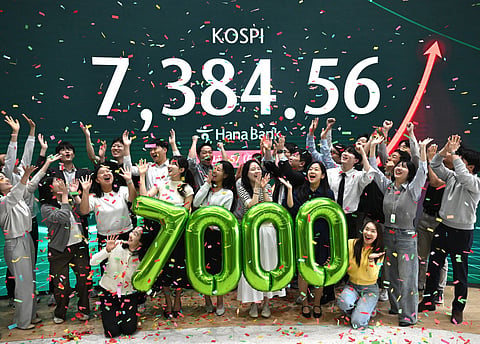 Currency dealers celebrate in front of a screen showing South Korea's benchmark stock index (KOSPI) during a ceremony celebrating it breaking 7,000 points in a foreign exchange dealing room at the Hana Bank headquarters in Seoul. File photo taken on May 6, 2026.