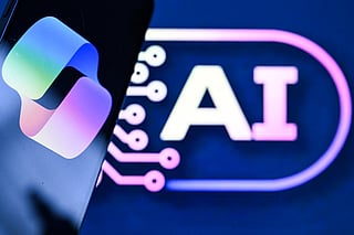 A photo taken on May 7, 2026 shows the letters AI for Artificial Intelligence on a laptop screen (R) next to the logo of the Microsoft's Copilot chatbot application on a smartphone screen in Frankfurt am Main, western Germany.