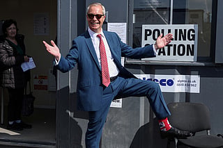 Reform UK leader Nigel Farage poses to show off his socks as he visits a polling station in Walton-on-the-Naze, eastern England on May 7, 2026, to cast his vote in the local elections.