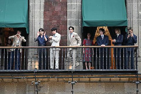 Mexico's President Claudia Sheinbaum looks at South Korean K-pop band BTS as they acknowledge fans from the balcony of the National Palace, at Zocalo square in Mexico City on May 6, 2026.