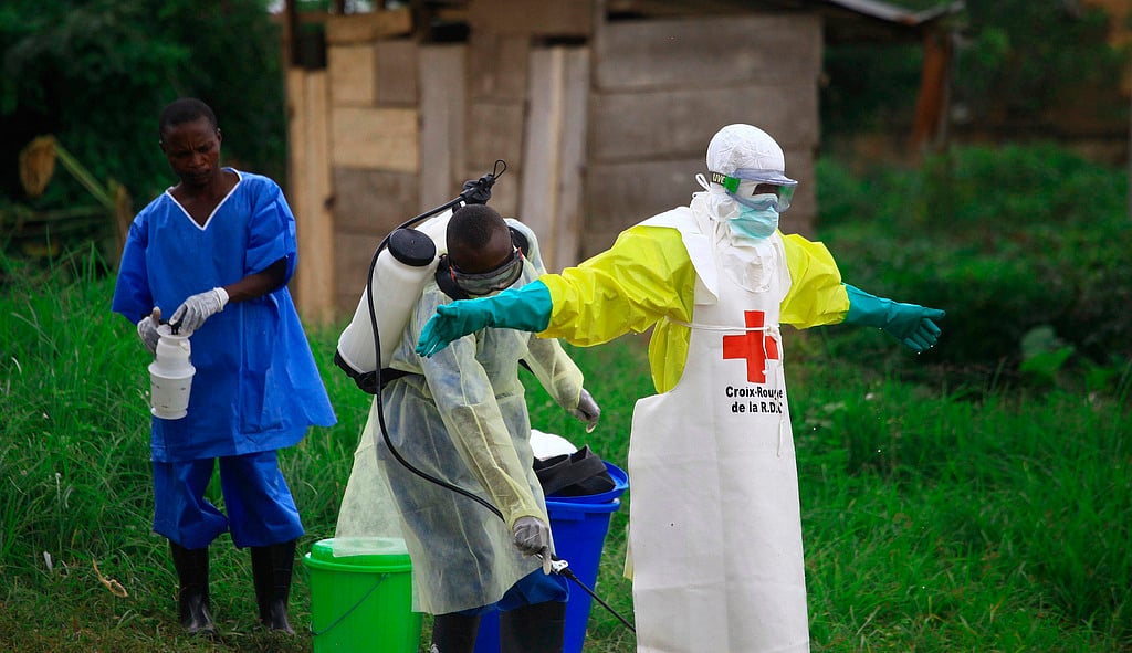 A health worker sprays disinfectant on his colleague after working at an Ebola treatment center in Beni