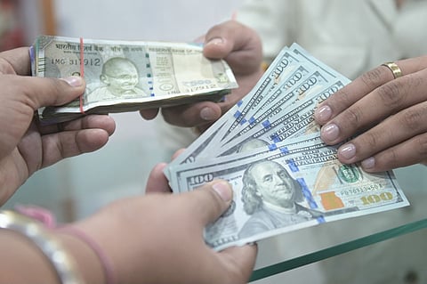 People holding US dollar and Indian rupee currency notes pose for a photograph at a foreign exchange office in Amritsar on May 16, 2026.