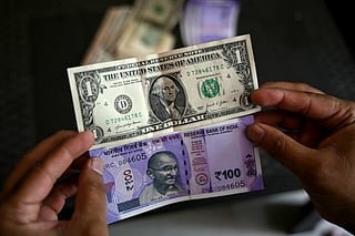 A man holds an Indian one hundred rupee (below) and a US dollar currency note at a foreign exchange office in Hyderabad on May 16, 2026.