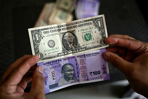 A man holds an Indian one hundred rupee (below) and a US dollar currency note at a foreign exchange office in Hyderabad on May 16, 2026.
