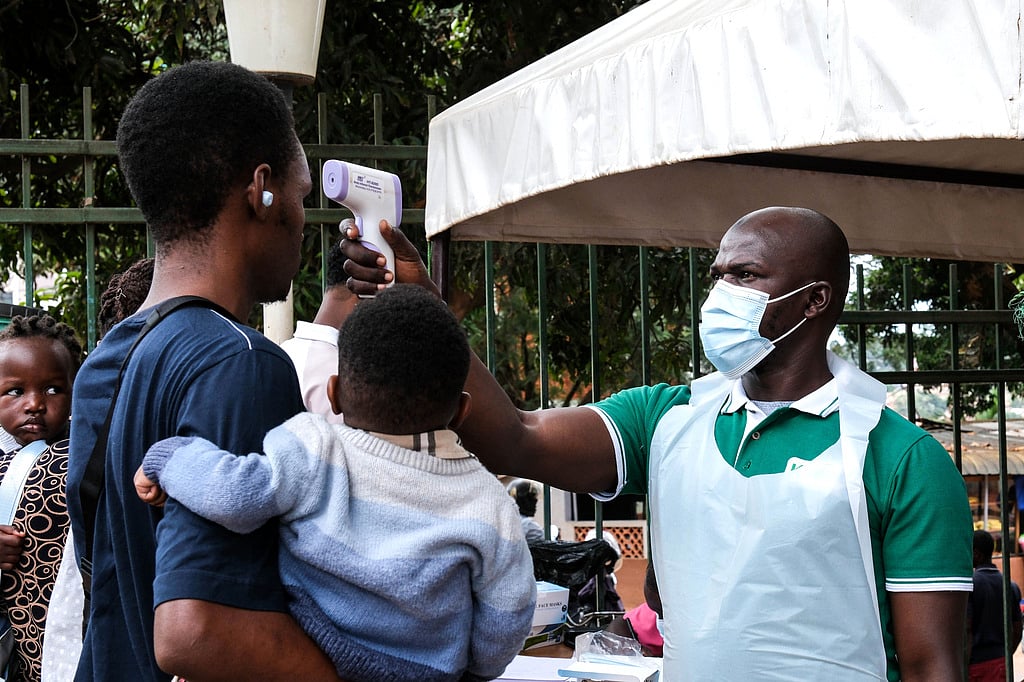 A health official uses a thermometer to screen people in front of Kibuli Muslim Hospital in Kampala, Uganda, Saturday, May 16, 2026.  