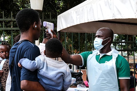 A health official uses a thermometer to screen people in front of Kibuli Muslim Hospital in Kampala, Uganda, Saturday, May 16, 2026.  