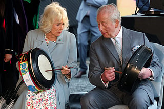 Britain's King Charles III and Britain's Queen Camilla play bodhran drums, traditional Irish drums, as they watch dancers perform to mark Fleadh Cheoil na hÉireann coming to Belfast this August, at Thompson Dock in Belfast, Northern Ireland on May 19, 2026, during their three-day visit to Northern Ireland.
