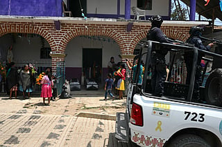 A Mexican state police vehicle drives past a funeral of members of a Mexican self-defense group after an attack by alleged members of Los Ardillos drug cartel in Alcozacan, Guerrero state, Mexico on May 20, 2026.