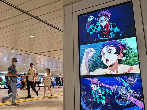 People walk past digital billboards advertising the upcoming release of the video game "Demon Slayer: Kimetsu no Yaiba – The Hinokami Chronicles 2"