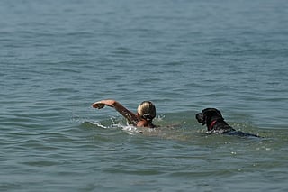 A swimmer and dog enjoy the cool sea temperatures off the beach in Brighton, on the south coast of England on May 25, 2026, as Monday is expected to be the hottest bank holiday ever, with heatwave conditions spreading to parts of southeast England and London.