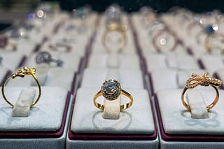 Diamond-encrusted gold rings are displayed in a storefront of a shop.