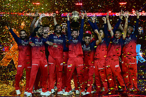 Royal Challengers Bengaluru cricket players celebrate with the trophy after winning the 2026 Indian Premier League (IPL) T20 final match against Gujarat Titans at the Narendra Modi Stadium in Ahmedabad on June 1, 2026.