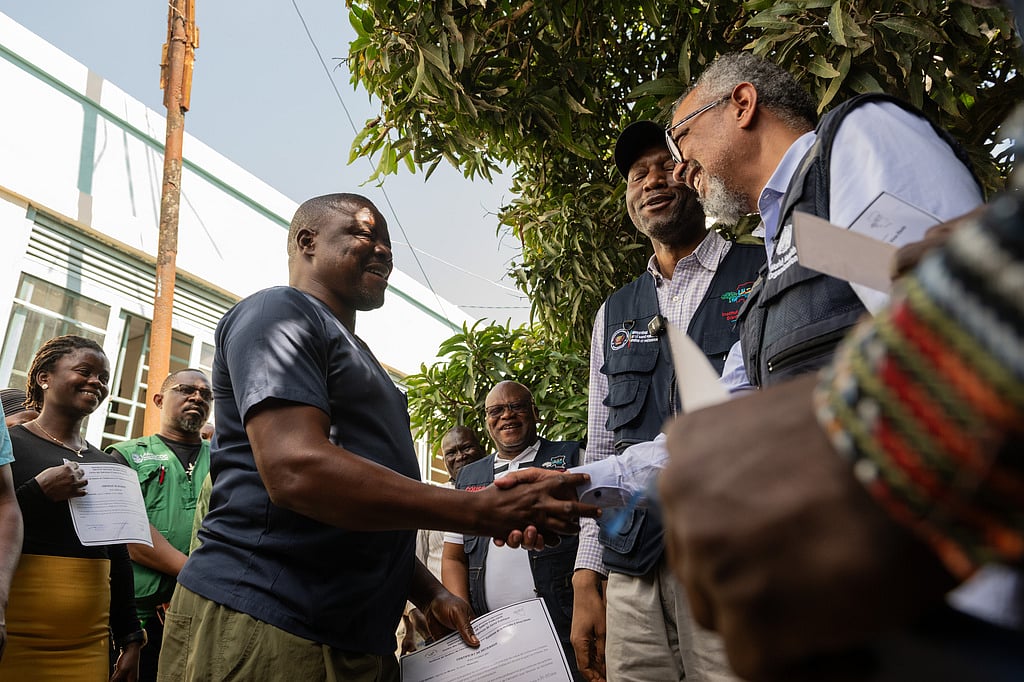 Director General of the World Health Organisation (WHO), Tedros Adhanom Ghebreyesus, right, shakes hands with Ezo Etienne, a health worker who recovered from Ebola in Bunia, Congo, Sunday, May 31, 2026. (AP Photo/Moses Sawasawa)
