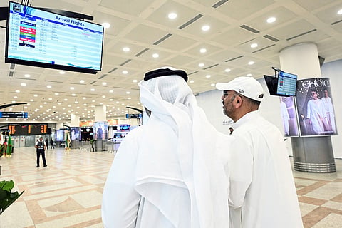 Kuwaiti men look at a screen displaying flight arrival information at Kuwait International Airport in Kuwait City on June 1, 2026, as the airport resumes operations following a phased reopening plan.